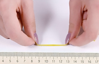 The marked paper strip measured flat against a metric ruler